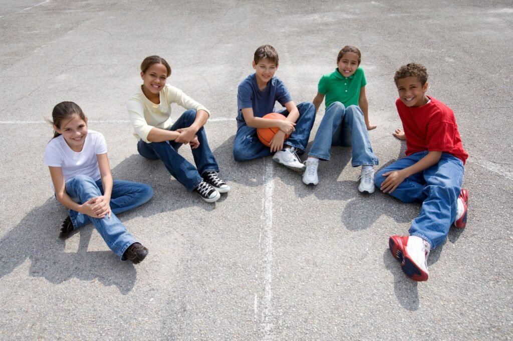 A diverse group of teenagers sitting on concrete, enjoying friendship and sports outdoors.